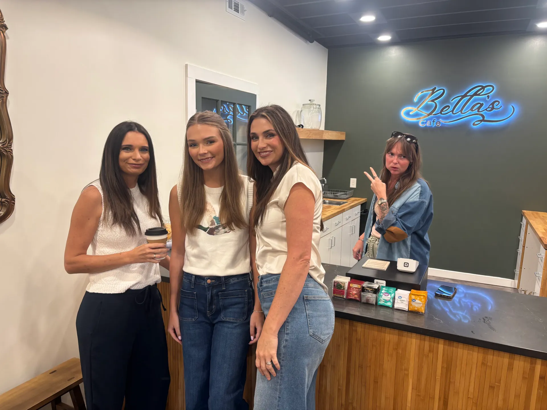 Women standing and serving at Cornerstone Church’s Bella’s Café coffee counter, with the café sign visible behind them